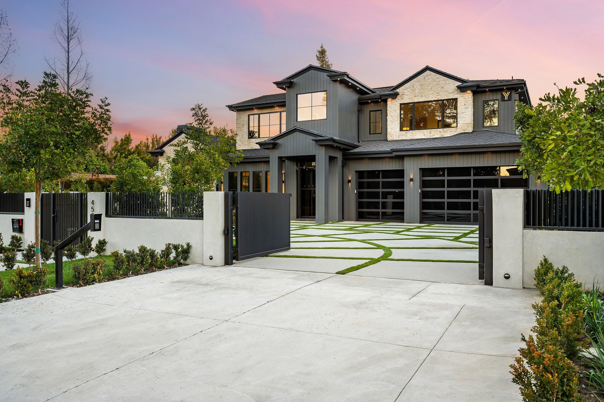 Modern luxury home with a sleek exterior design, landscaped driveway, and sunset sky